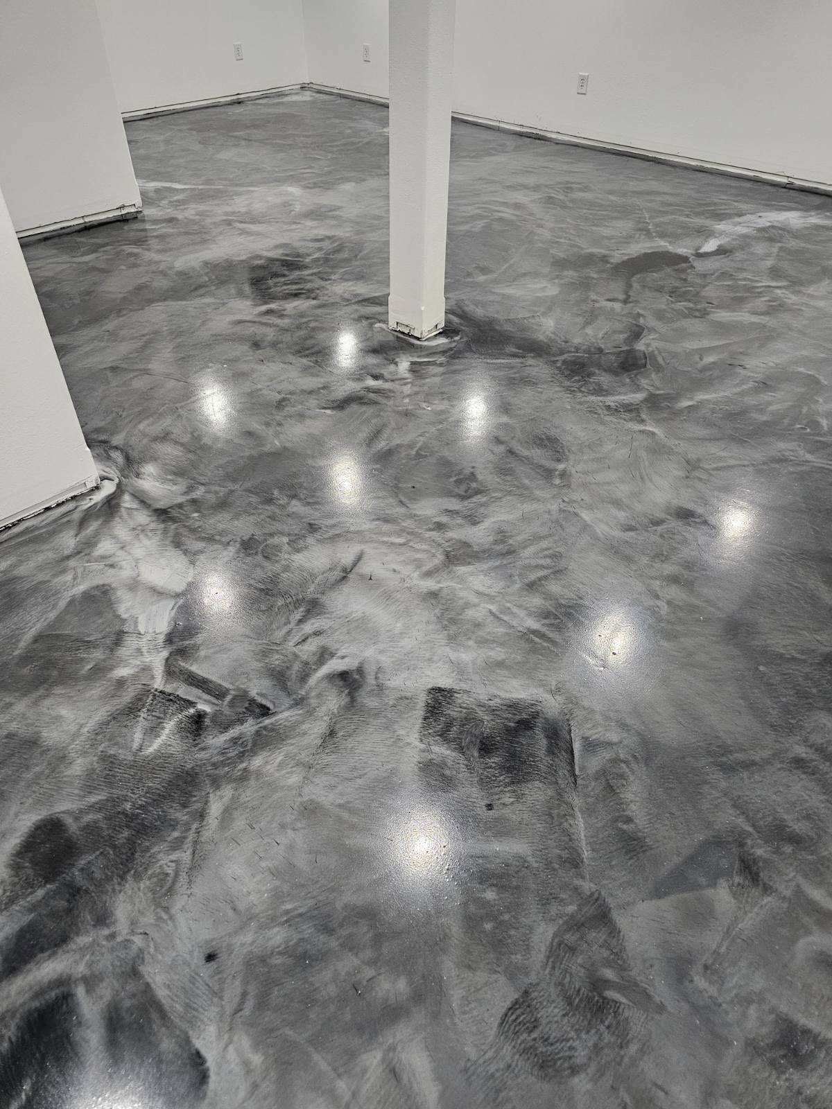 A black and white photo of a shiny metallic floor in a room.