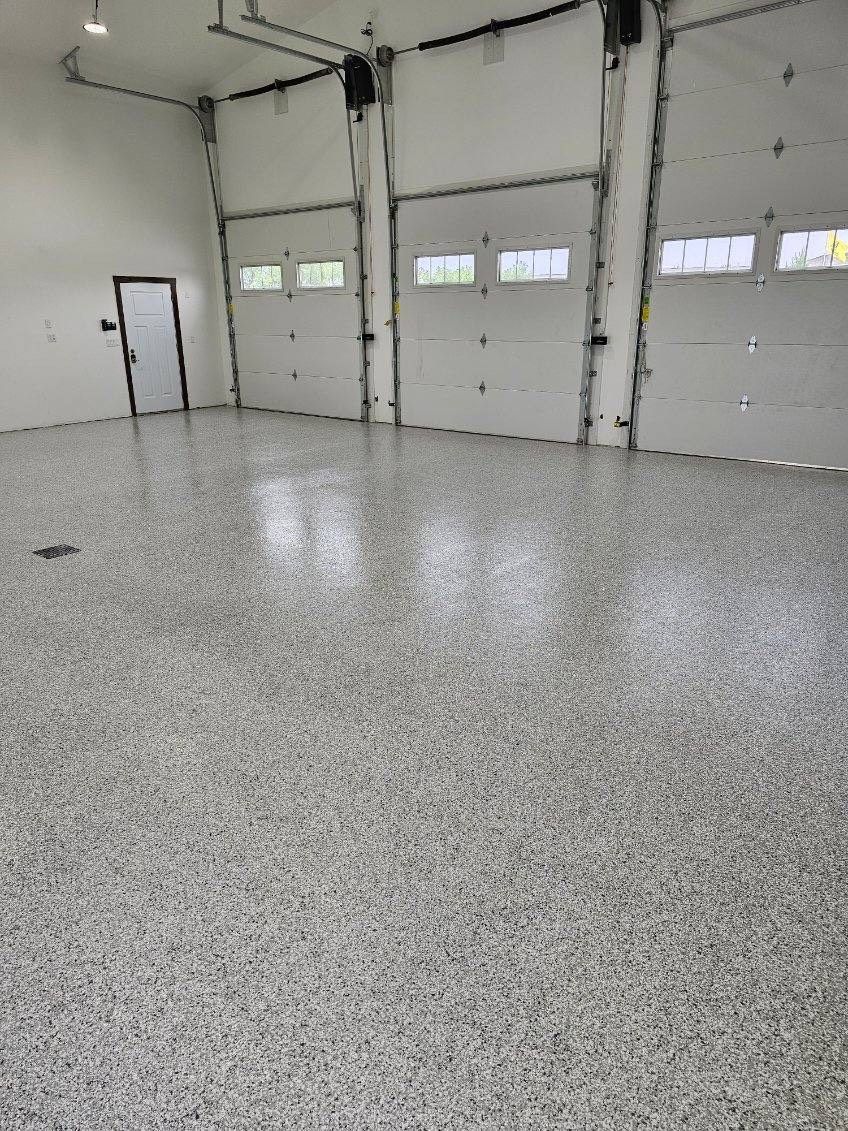 A large empty garage with a concrete floor and garage doors.