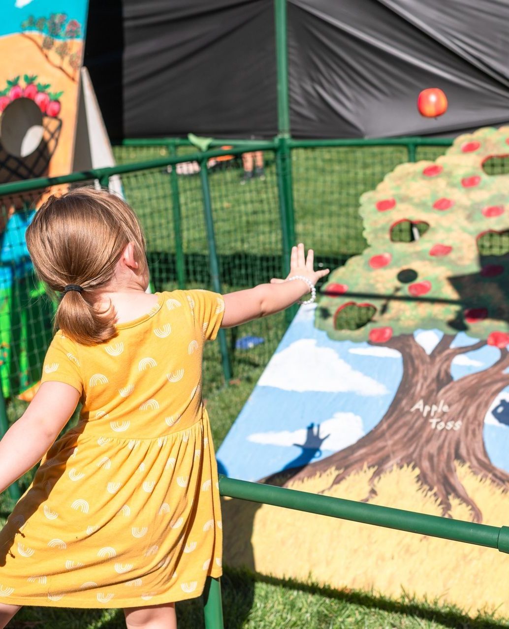 Young girl throwing apples in an apple game