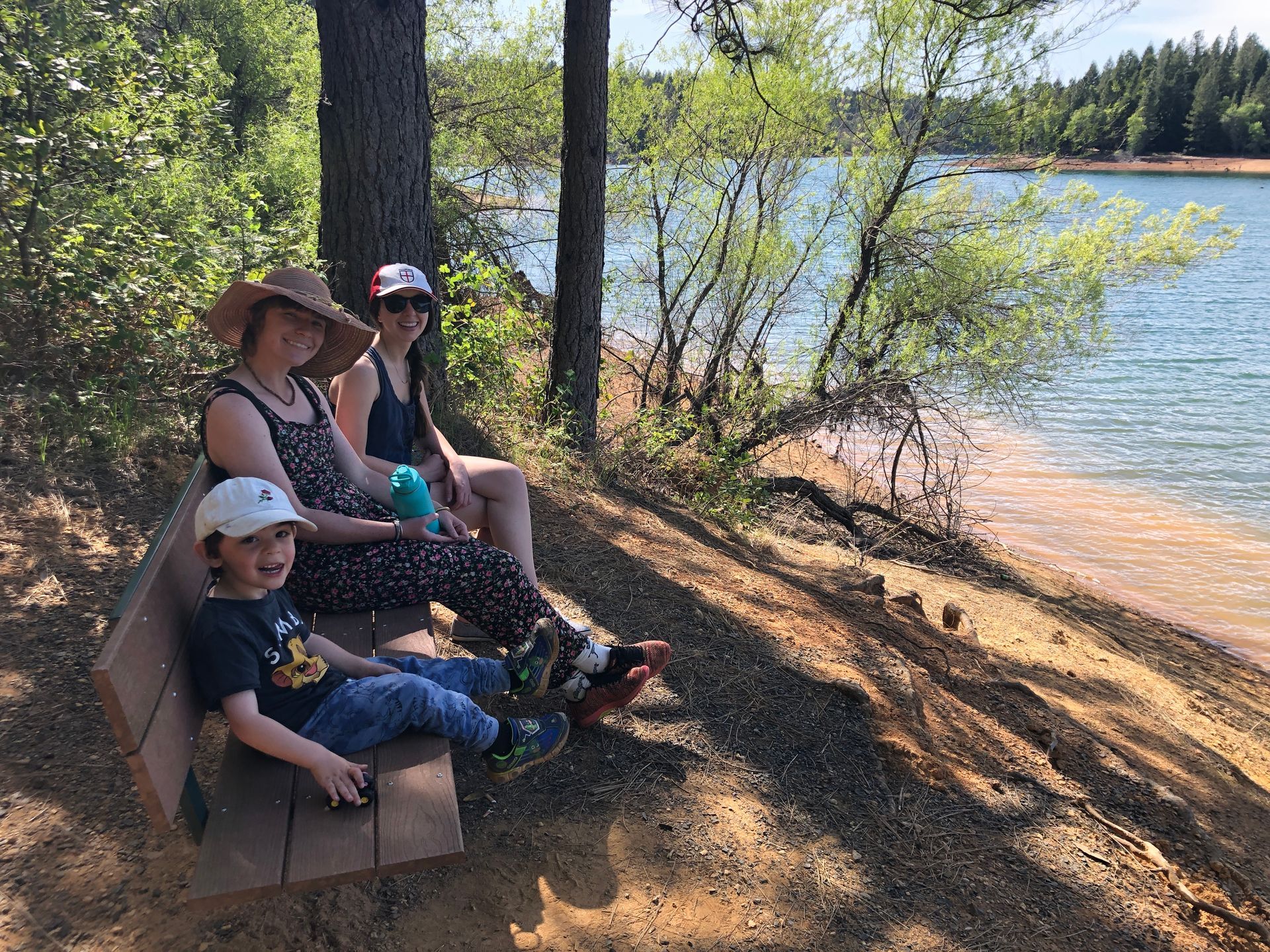 A group of people are sitting on a bench near paradise lake.