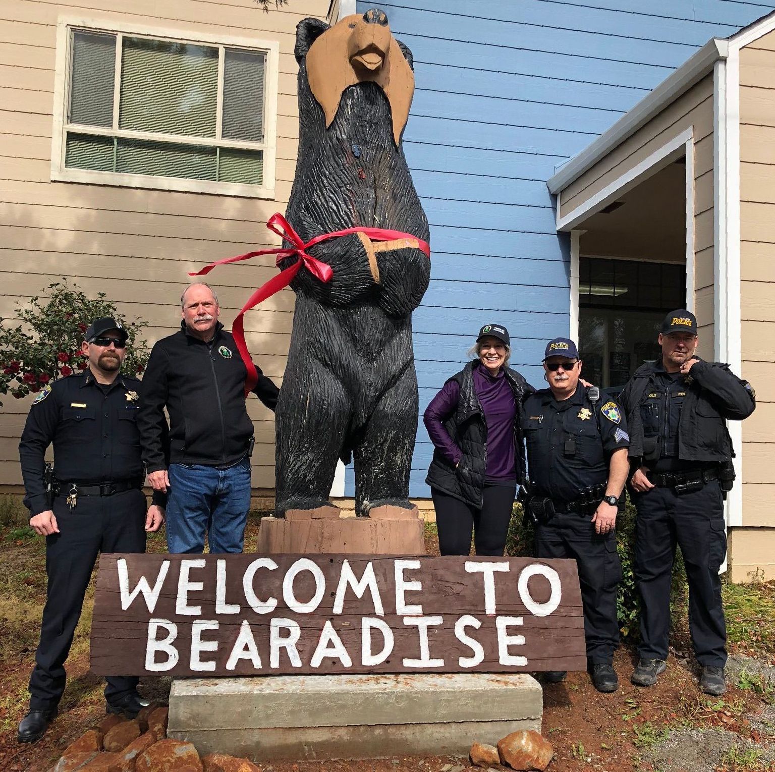 A group of police officers standing in front of a welcome to Paradise sign