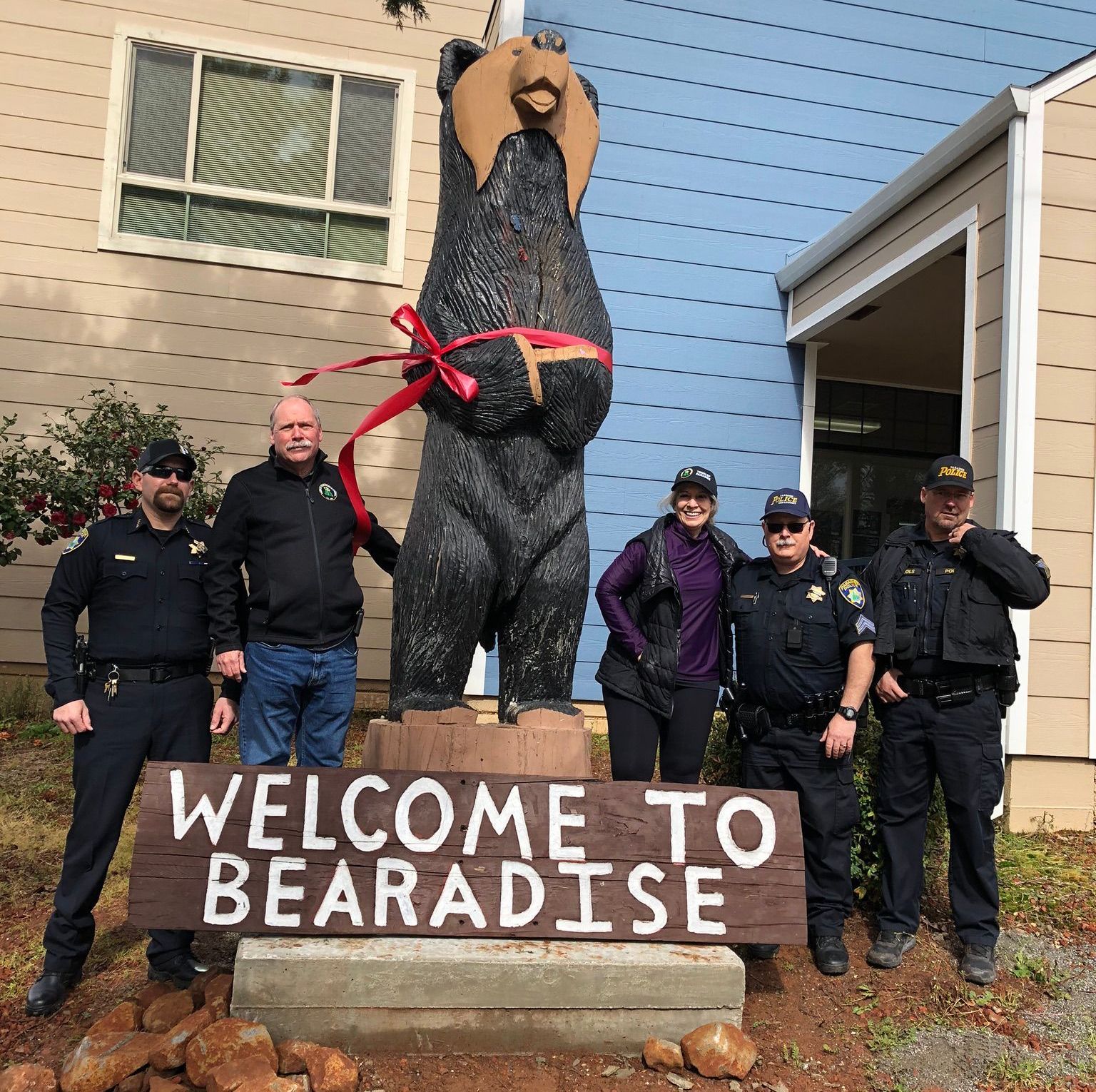 A group of police officers standing in front of a welcome to paradise sign
