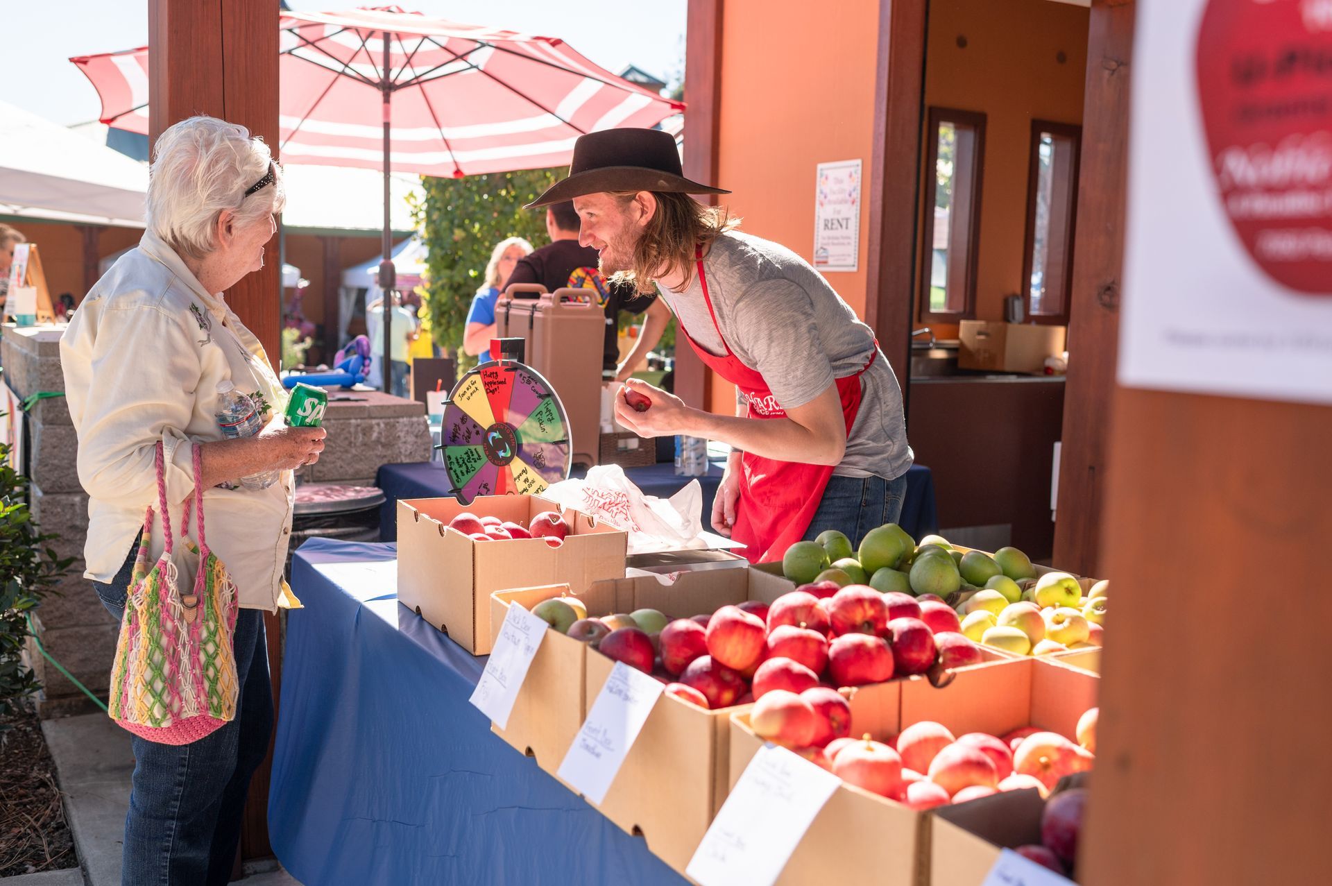 A man is selling apples to a woman at a farmers market  in Paradise and Magalia, California