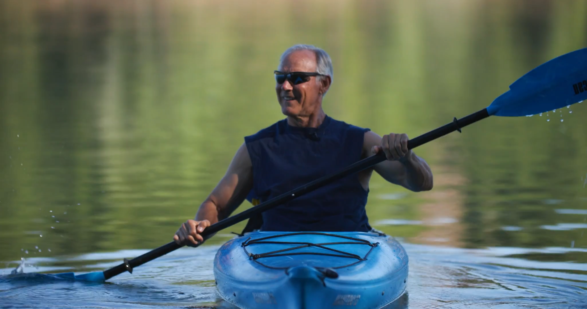 A man is paddling a kayak on paradise lake.