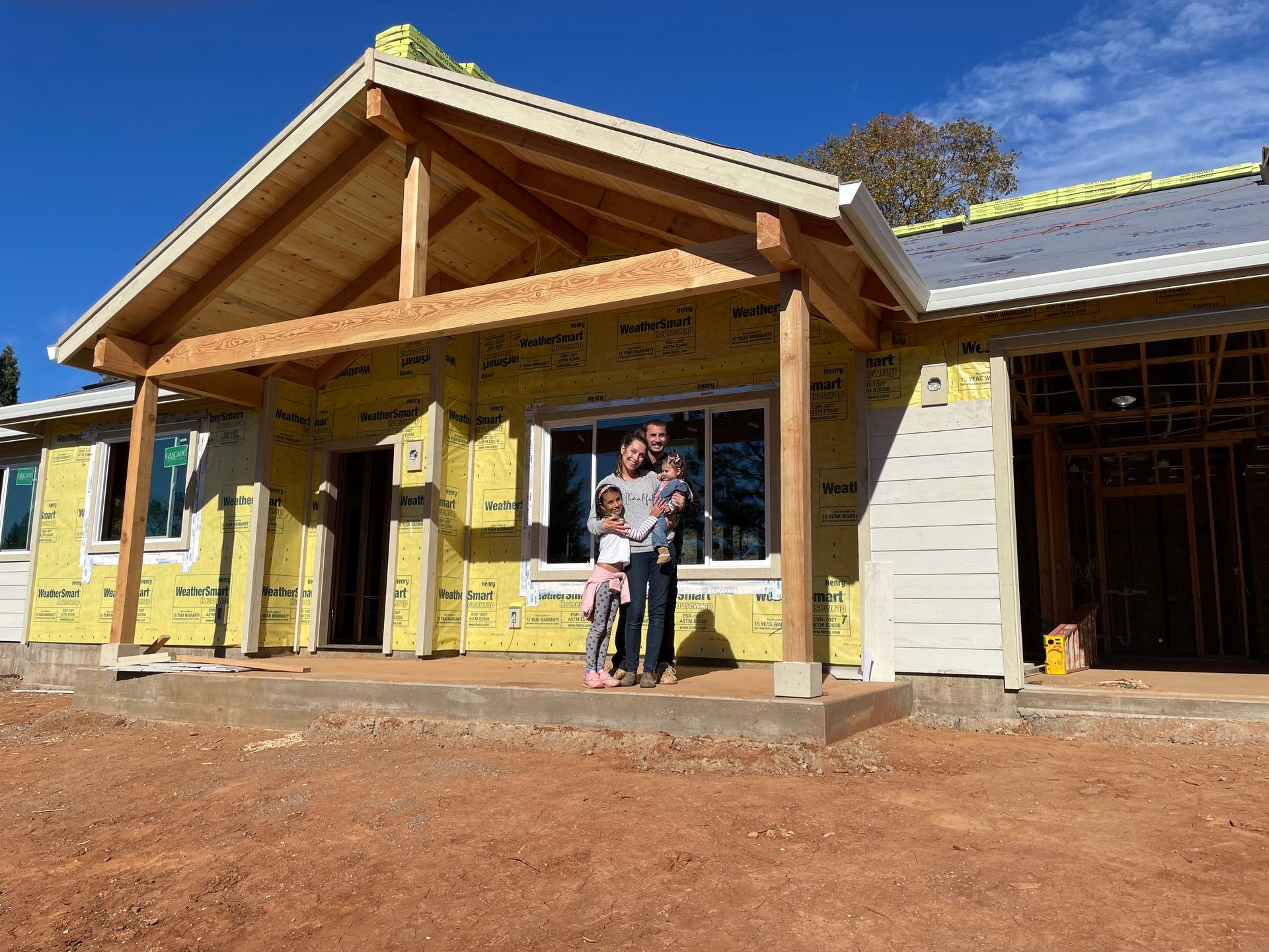 A family is standing on the porch of a house under construction in Paradise and Magalia, California
