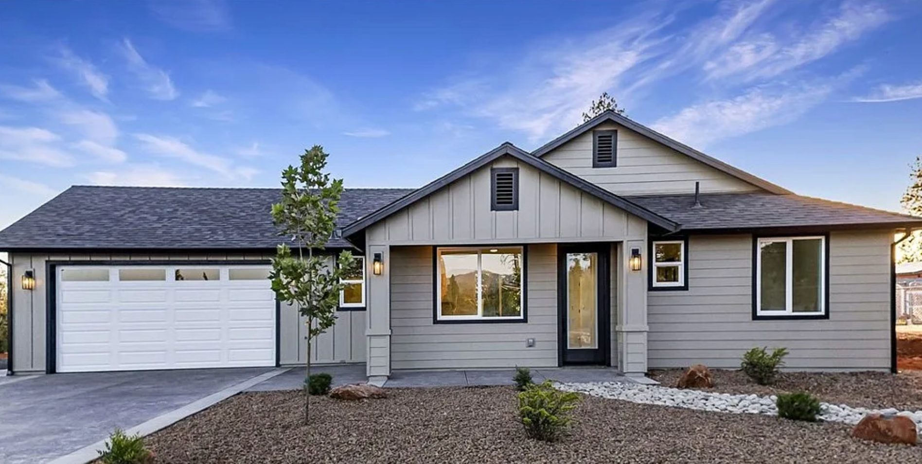 Modern gray single-story house with a two-car garage and front landscaping at sunset