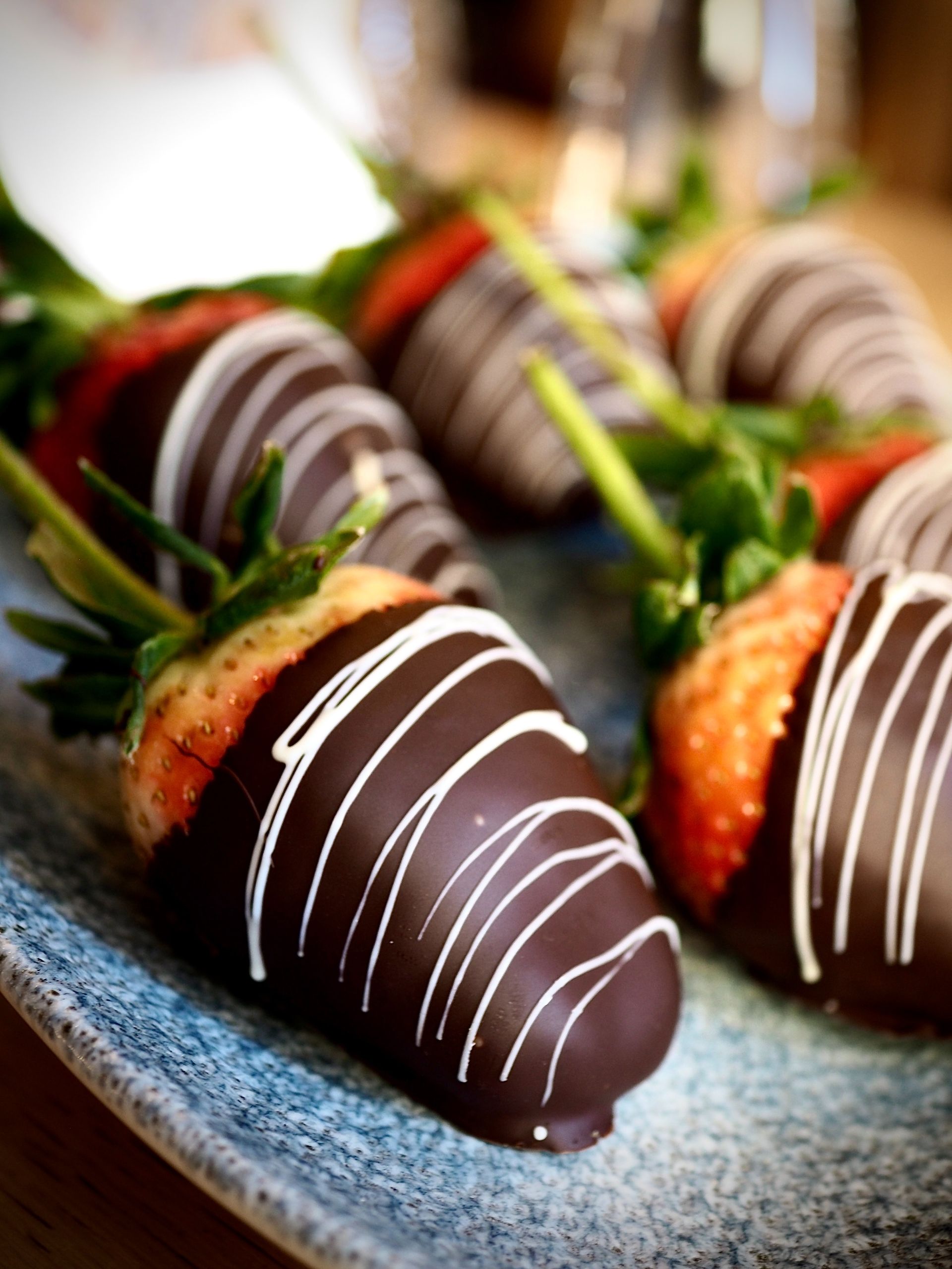 A blue plate topped with chocolate covered strawberries  in Paradise and Magalia, California
