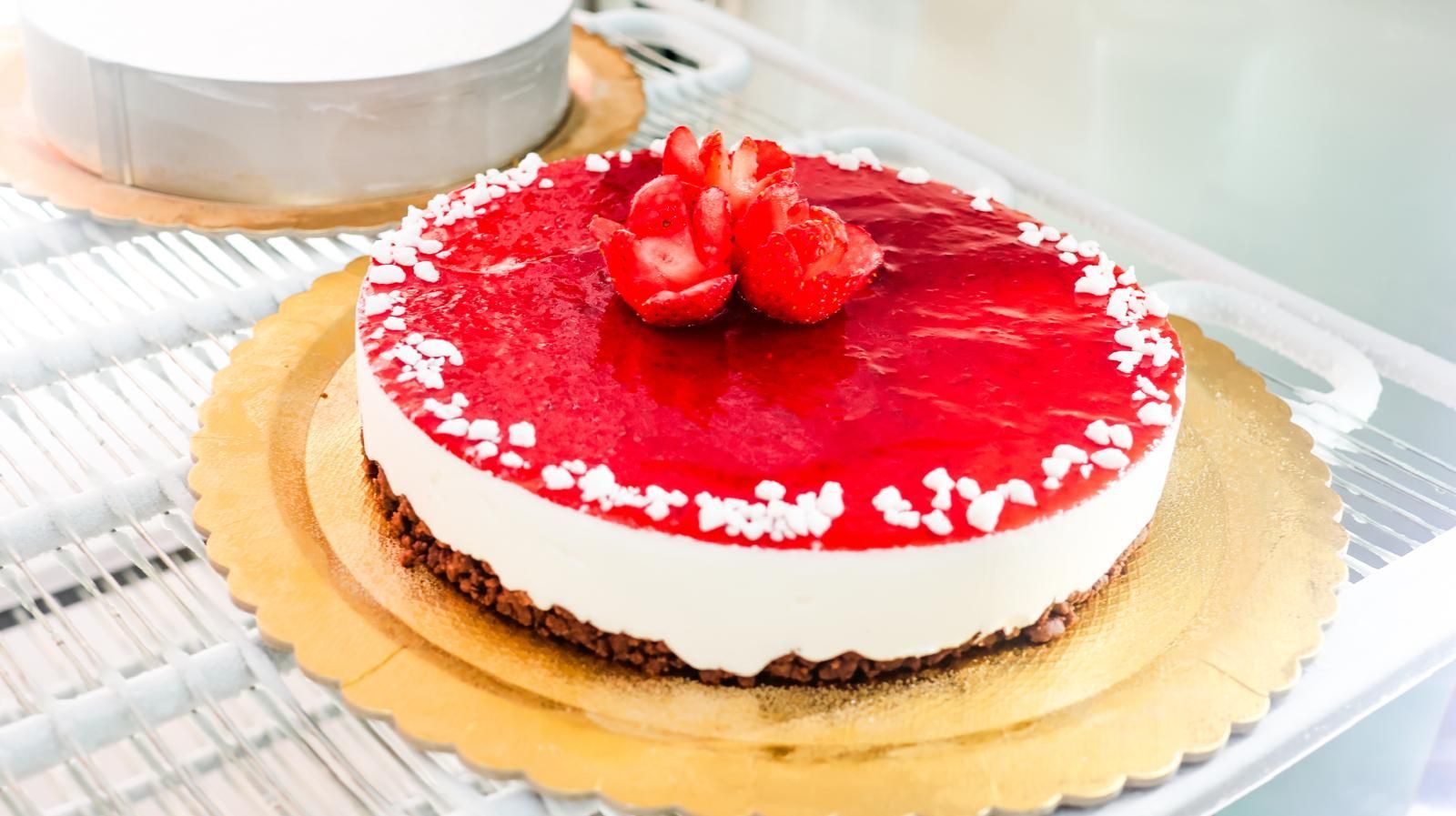 Una cheesecake con fragole sopra è appoggiata su un vassoio nel frigorifero.