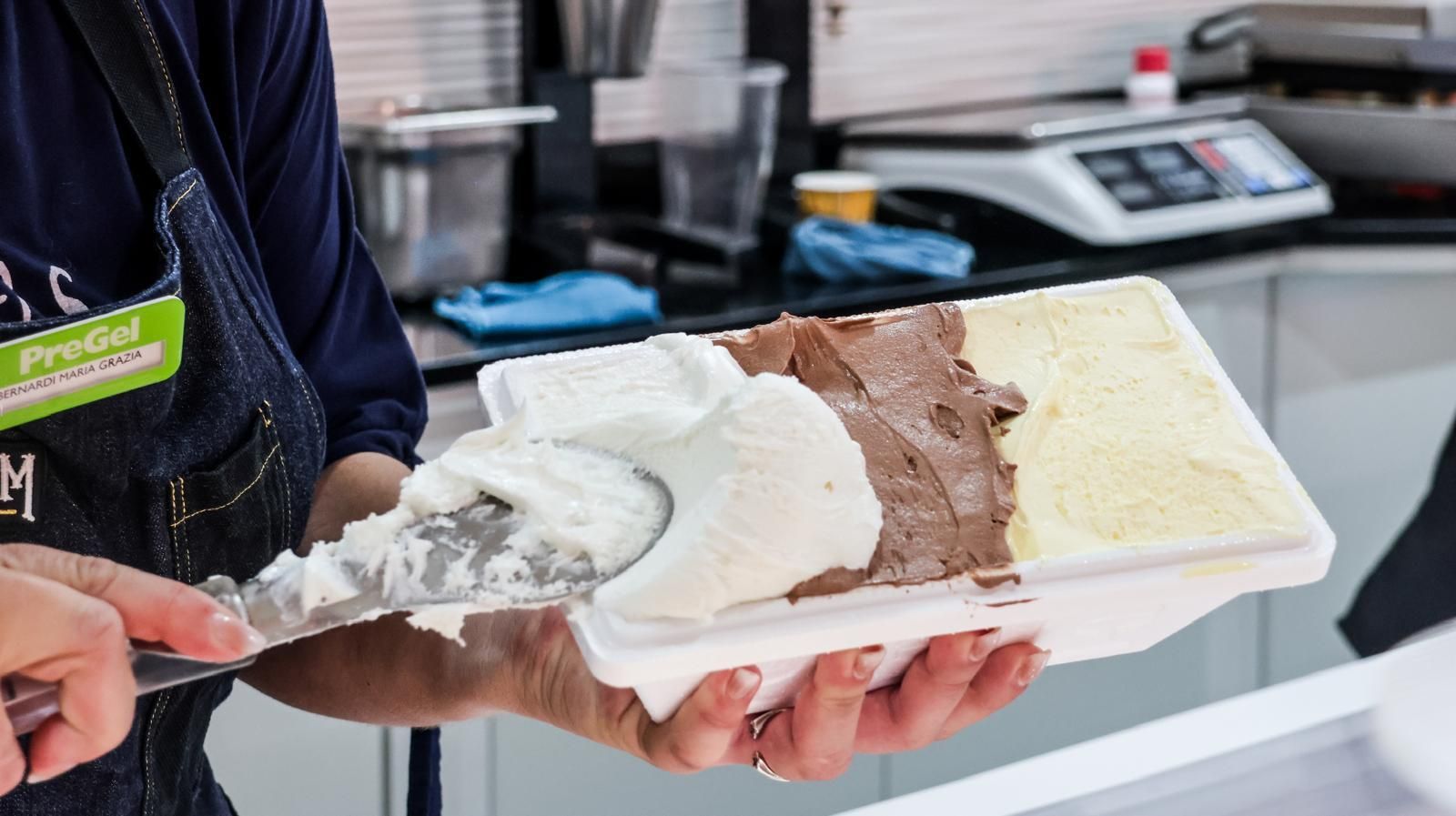 Una persona tiene in mano un contenitore di gelato con una spatola.
