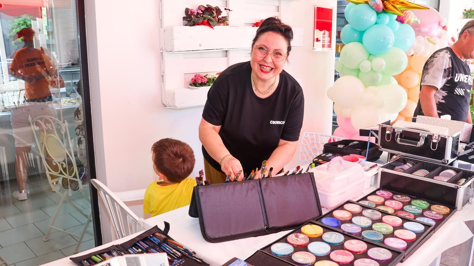 Una donna è in piedi davanti a un tavolo con una tavolozza di trucchi.