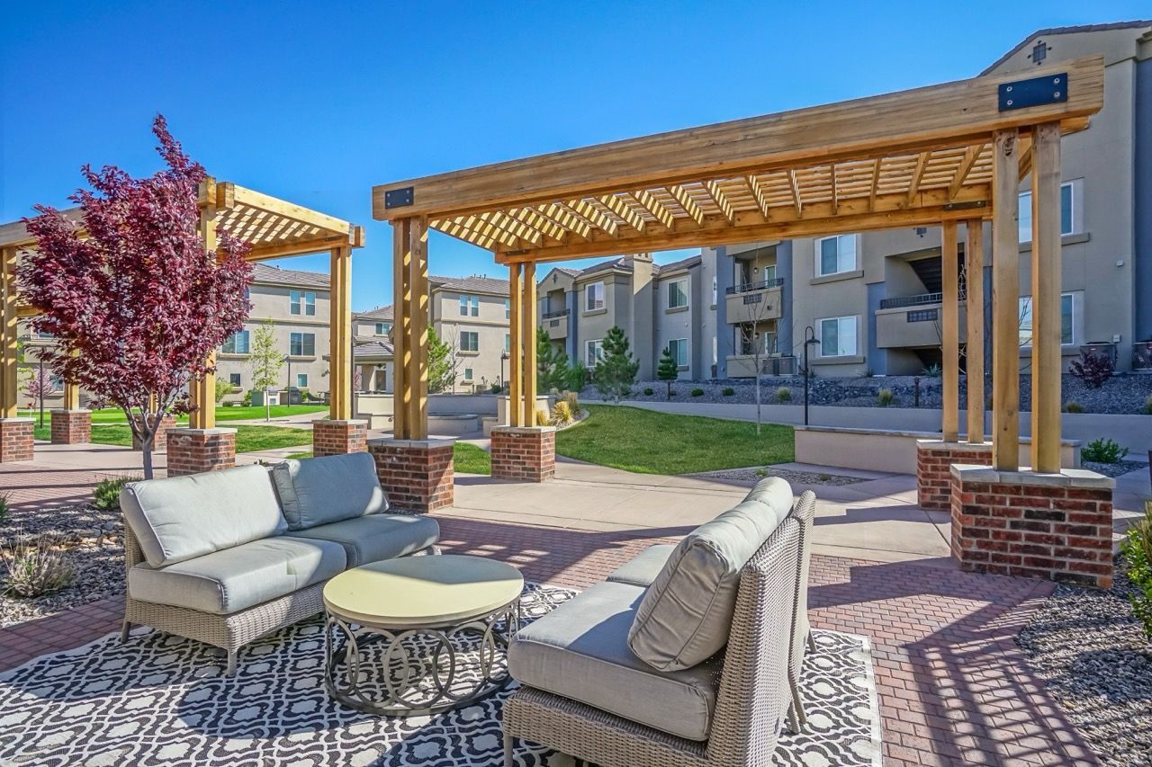 Outdoor communal seating area under wooden pergolas with brick-paver plaza
