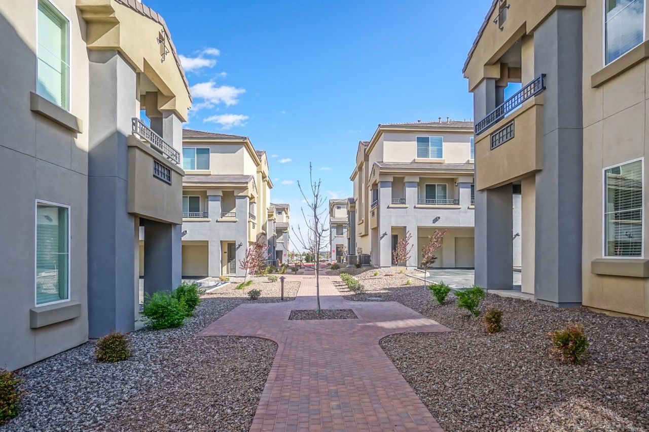 Exterior courtyard between apartment buildings with a brick walkway and gravel landscaping.