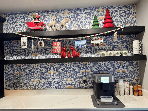 A Christmas with Santa, reindeer, trees, and photos displayed on shelves against blue floral wallpaper.