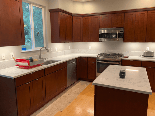 A kitchen with dark brown cabinets, white countertops, and stainless steel appliances. 