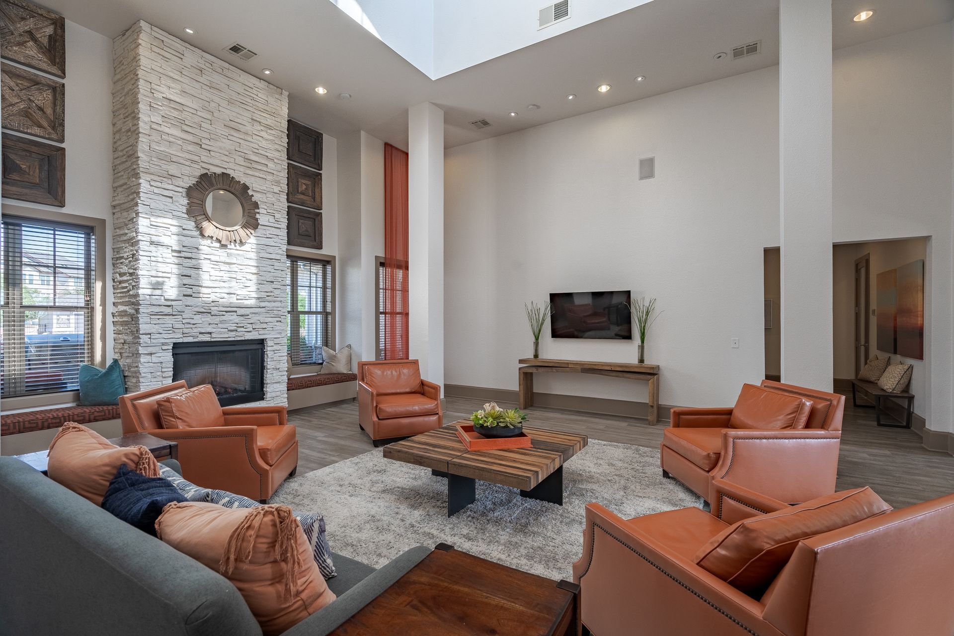 Communal lounge with a stone fireplace, orange leather chairs, and a wall-mounted TV.