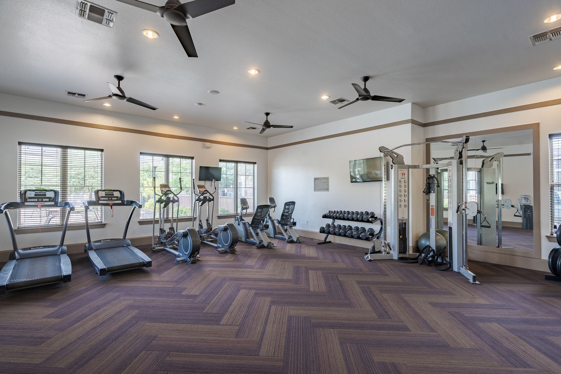 Interior view of a community gym with treadmills, ellipticals, and weight machines.