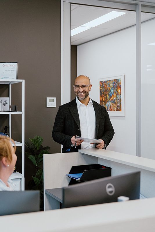 A Man In A Suit Is Standing At A Reception Desk In An Office — David Tamanika Solicitors in Ballarat Central, VIC