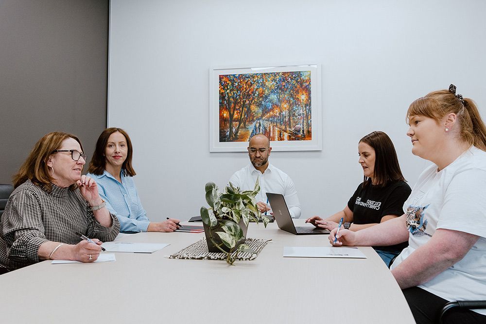 A Group Of People Are Sitting Around A Table In A Conference Room — David Tamanika Solicitors in Bacchus Marsh, VIC