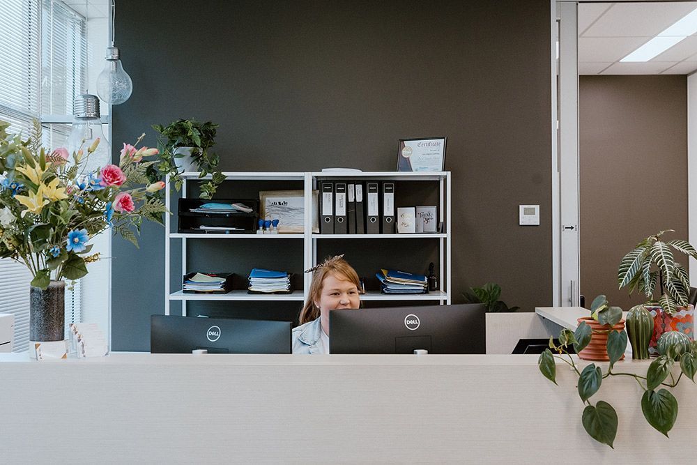 A Woman Is Sitting At A Desk In Front Of A Computer — David Tamanika Solicitors in Ballarat Central, VIC