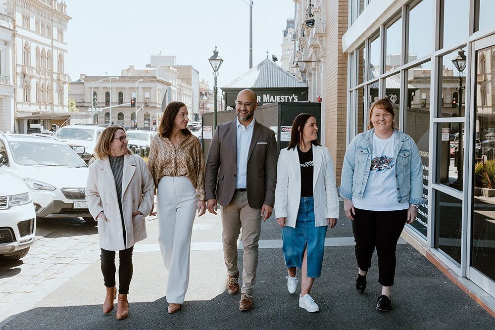 A Group Of People Are Walking Down A Sidewalk Holding Hands — David Tamanika Solicitors in Ballarat Central, VIC