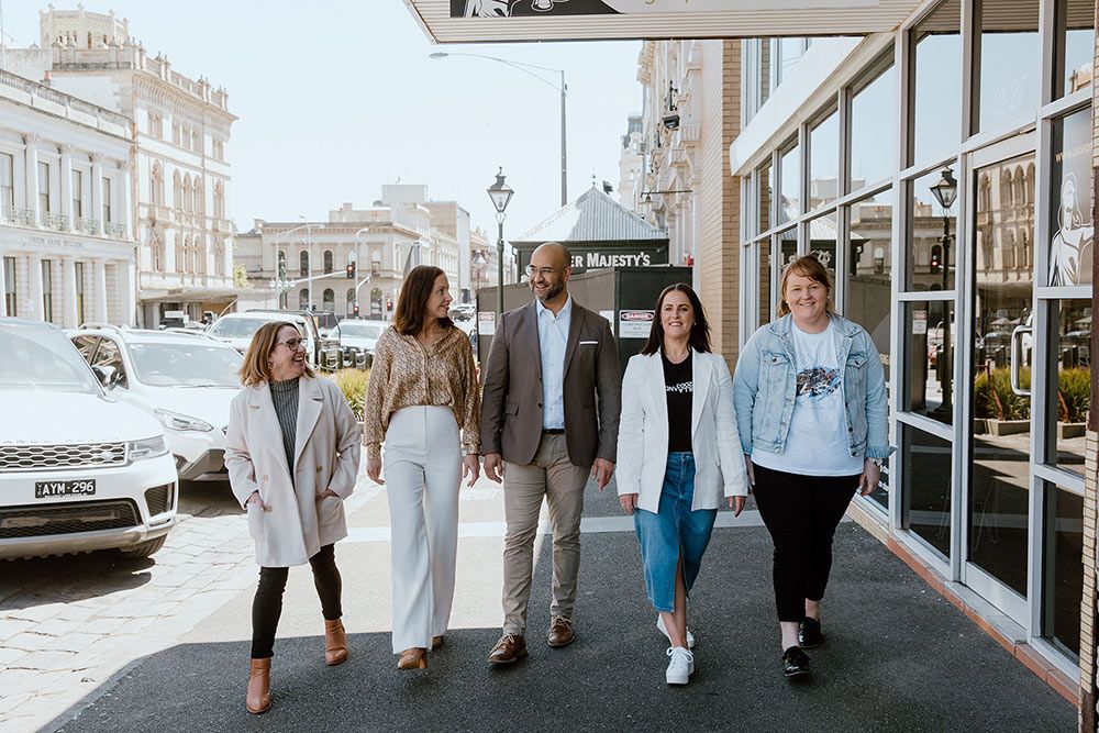 A Group Of People Are Walking Down A Sidewalk In Front Of A Building — David Tamanika Solicitors in Ballarat Central, VIC