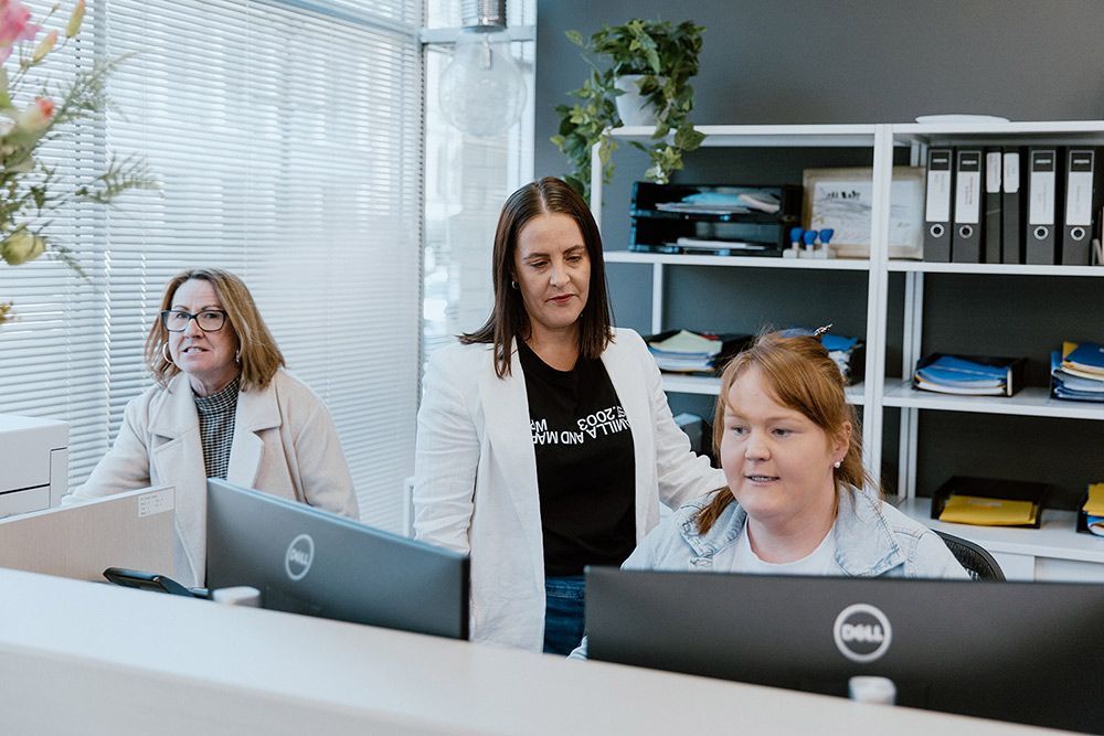 A Group Of Women Are Sitting At A Desk In Front Of A Computer — David Tamanika Solicitors in Ballarat, VIC