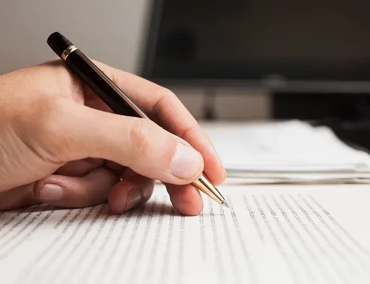 A Person Is Writing On A Piece Of Paper With A Pen — David Tamanika Solicitors in Ballarat Central, VIC