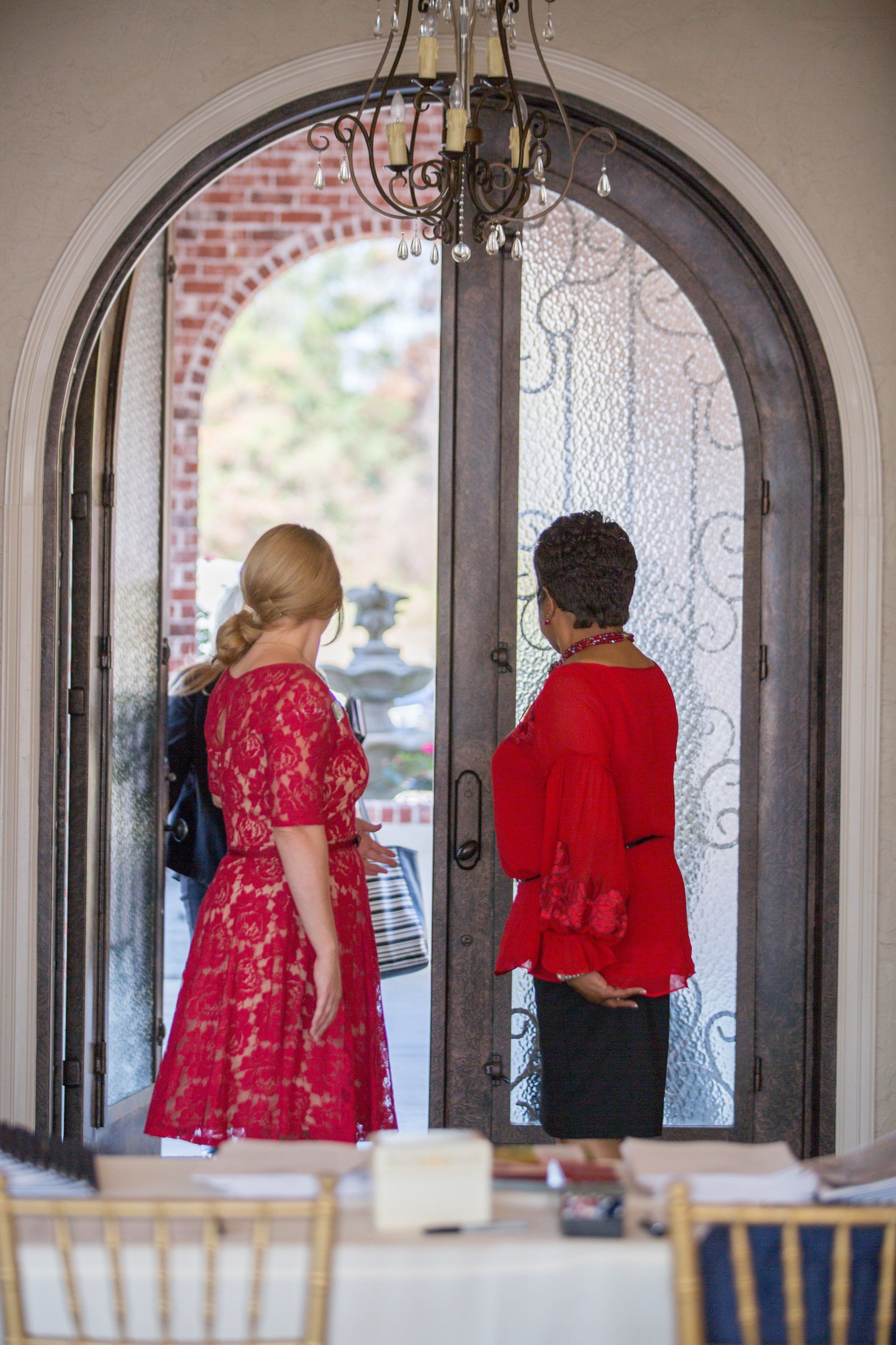 Two women are standing in front of a door talking to each other.