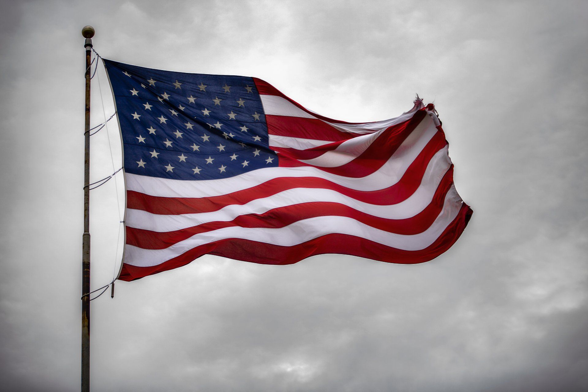 An american flag is waving in the wind against a cloudy sky