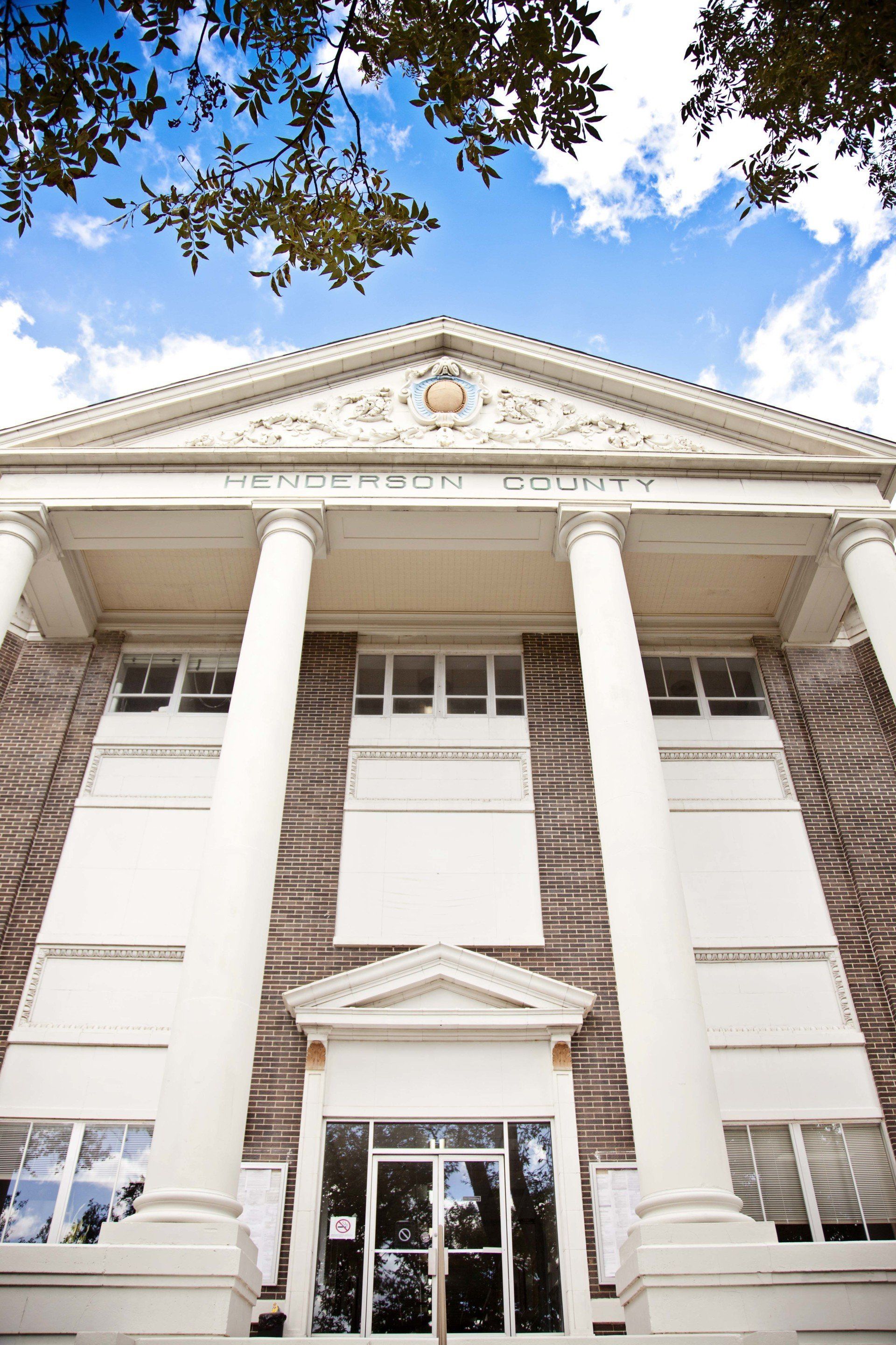 A brick building with white columns and a blue sky in the background