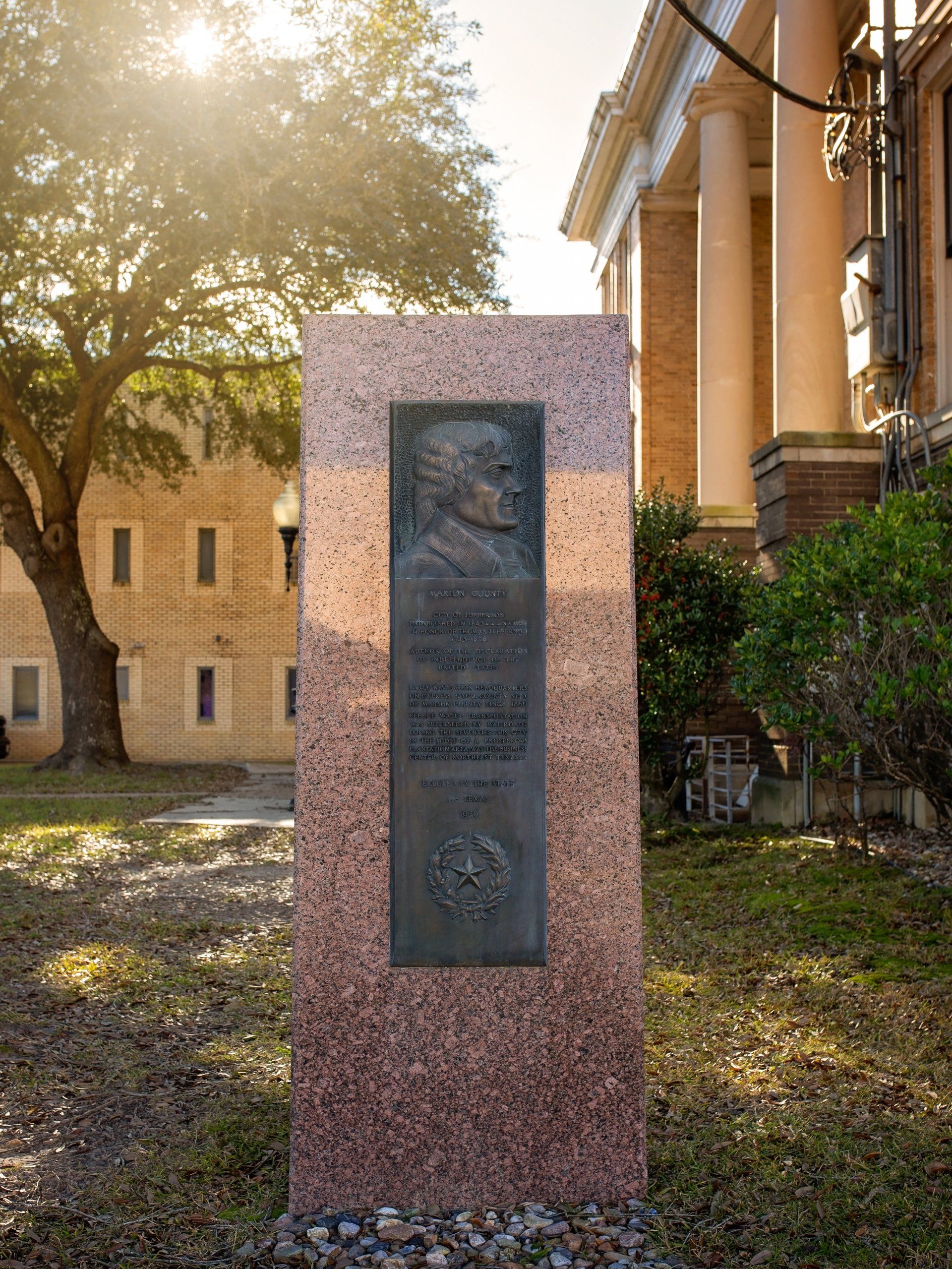 A statue of a man is sitting in front of a building.