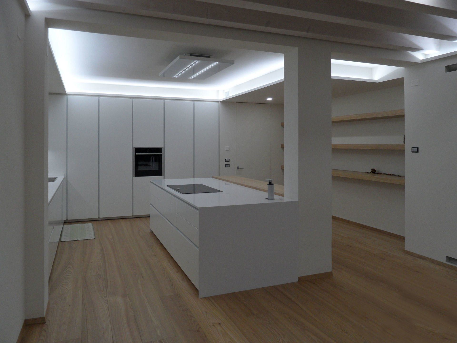 Ambiente cucina dal design moderno bianco opaco con isola, piano cottura induzione e torretta elettrificata