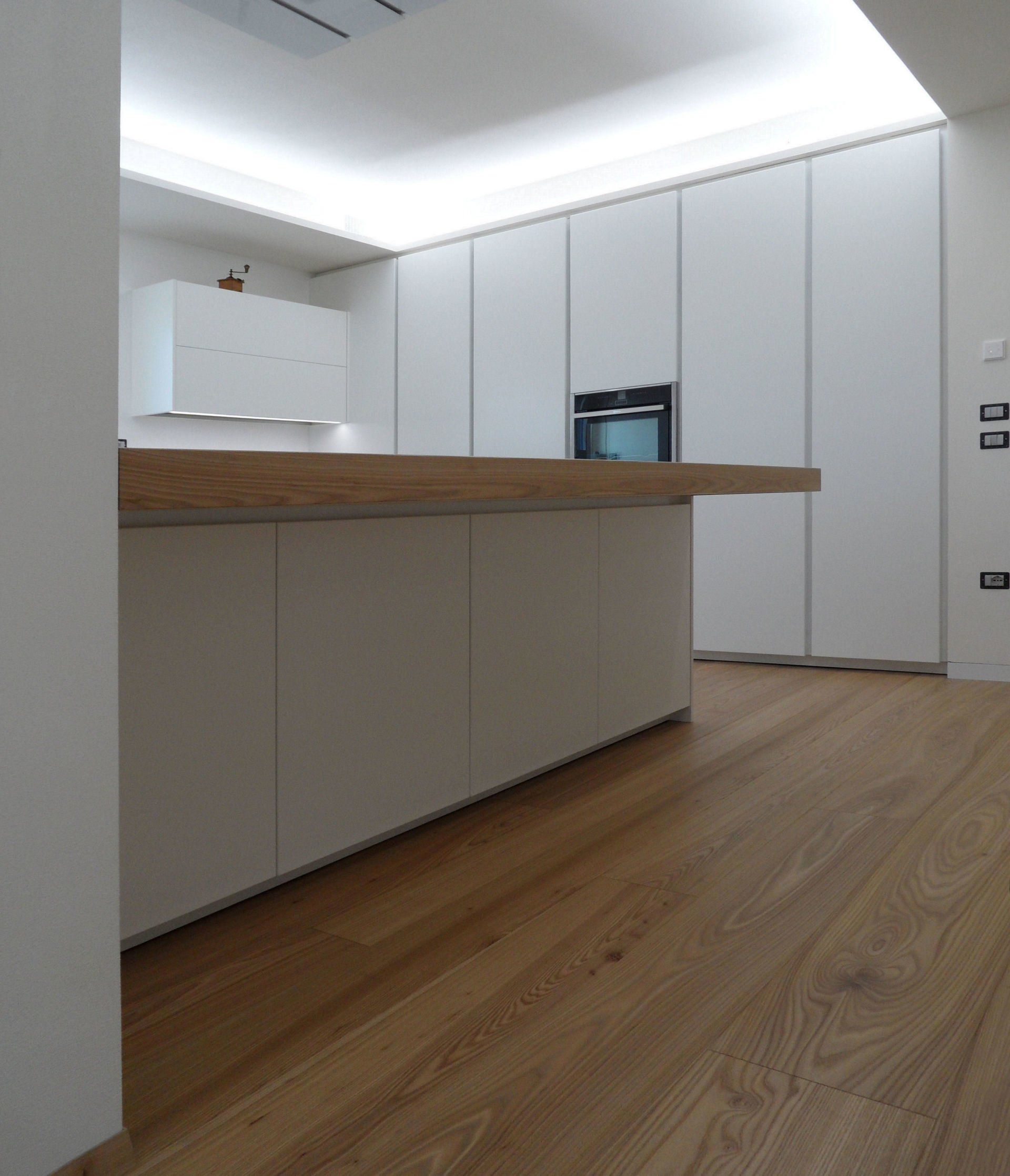 Ambiente cucina con isola dal design moderno bianco opaco su misura artigianale con particolari in quercia naturale