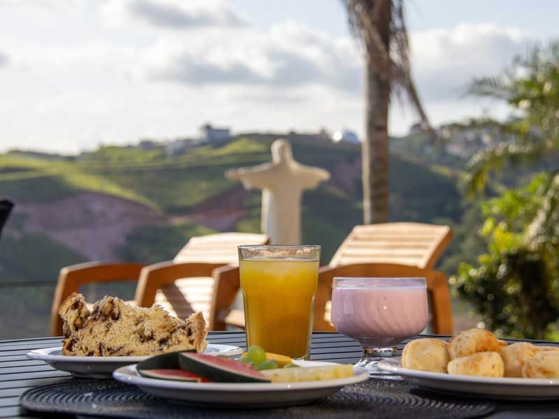 Café da manhã completo com vista para uma estátua; inclui bolo, frutas, bebidas e lanches.