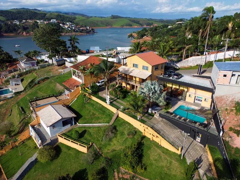 Vista aérea de edifícios com telhados vermelhos e bege perto de um lago e colinas verdes.
