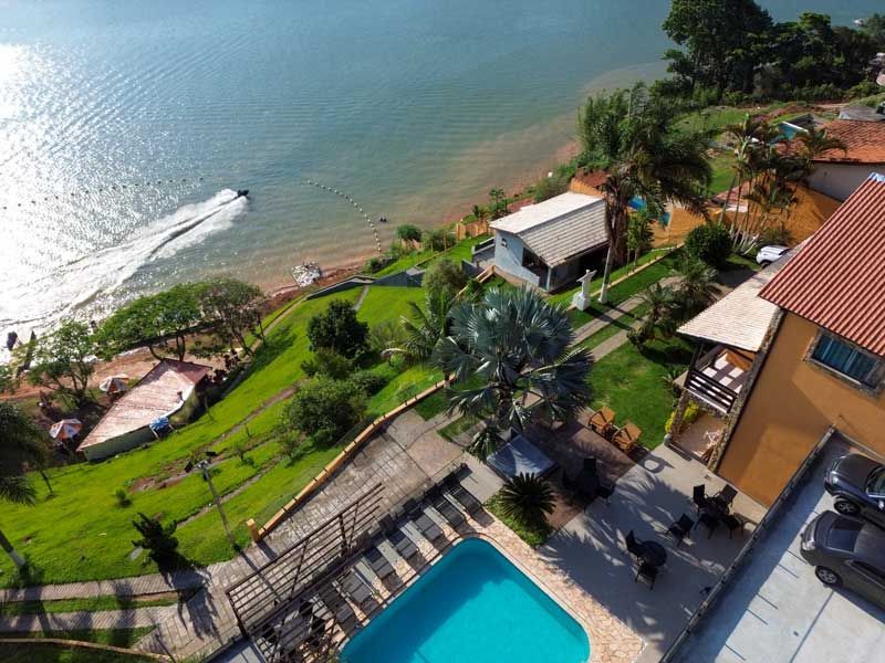 Vista aérea de um resort com piscina, edifícios e um lago com jet ski.
