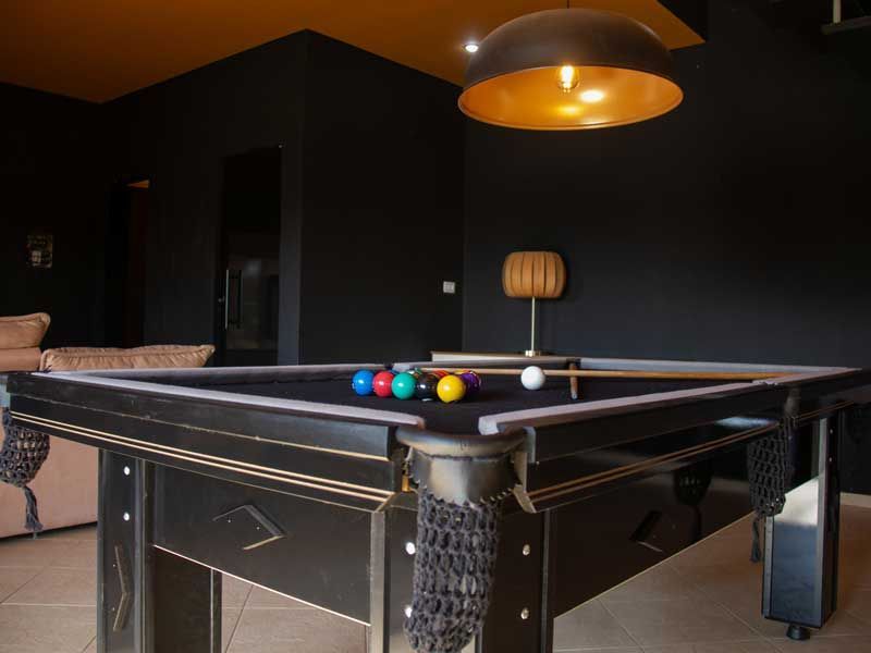 Mesa de bilhar preta em uma sala com paredes pretas e teto dourado.