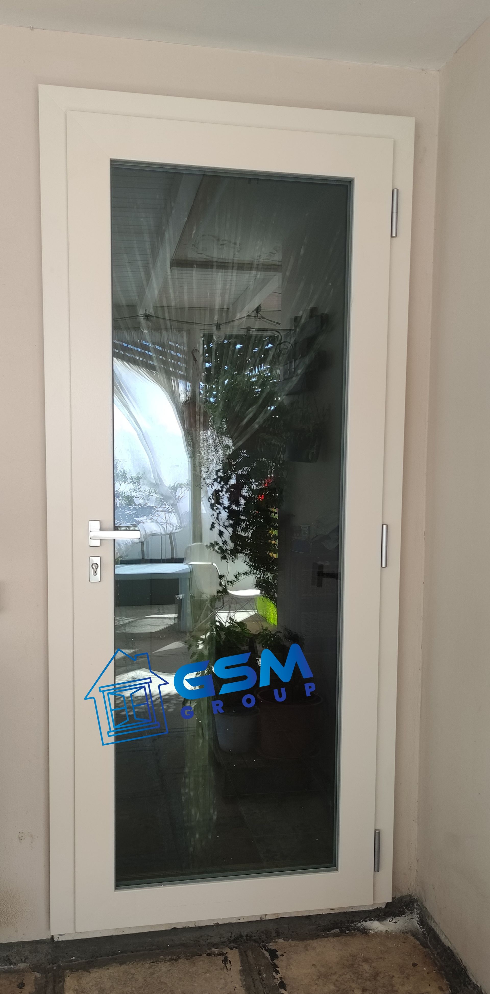 Una porta a pannello singolo in vetro bianco con maniglia argentata, incastonata su una parete chiara.