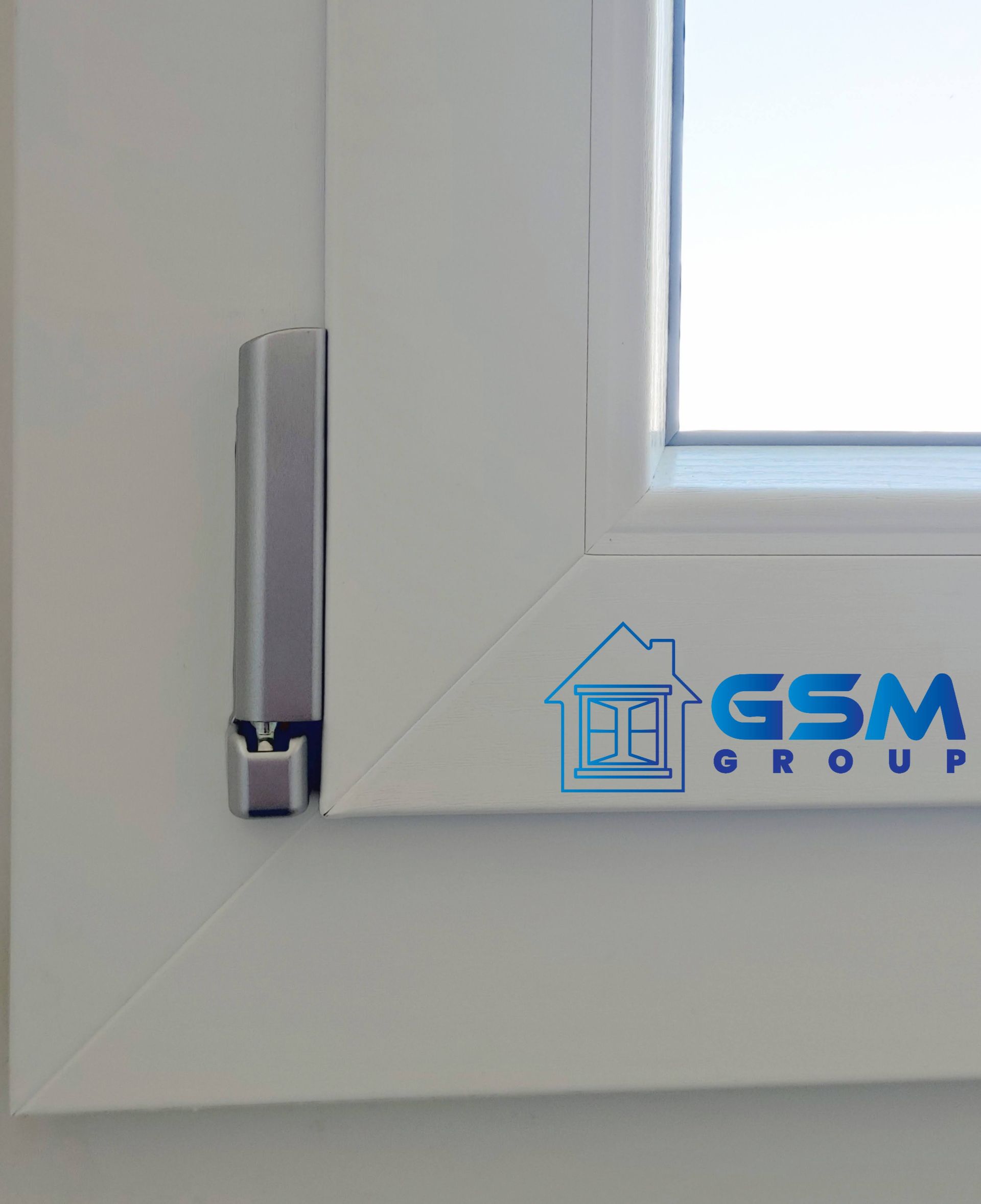 Primo piano di un telaio di finestra bianco con un chiavistello in metallo e un adesivo blu con il logo del Gruppo GSM.