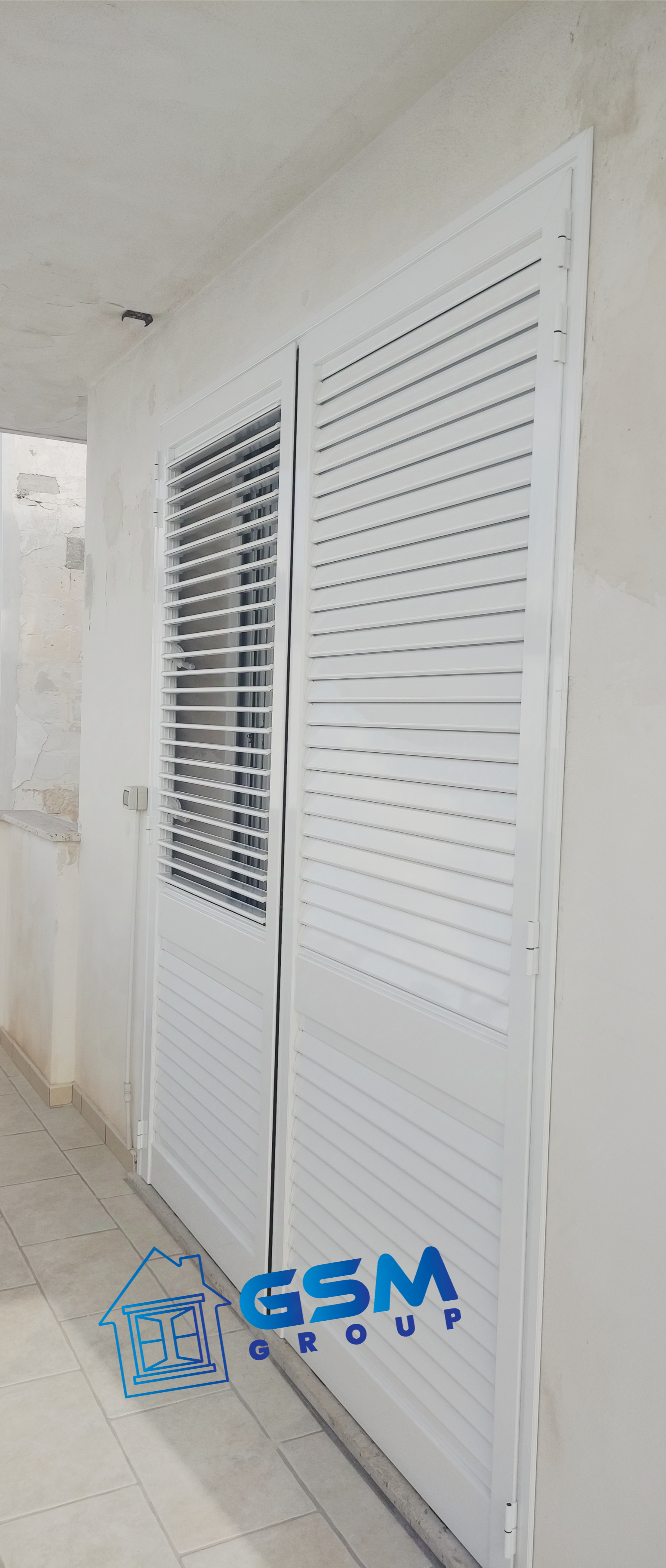 Persiane marroni si chiudevano su un muro color pesca sopra una base in mattoni di pietra.