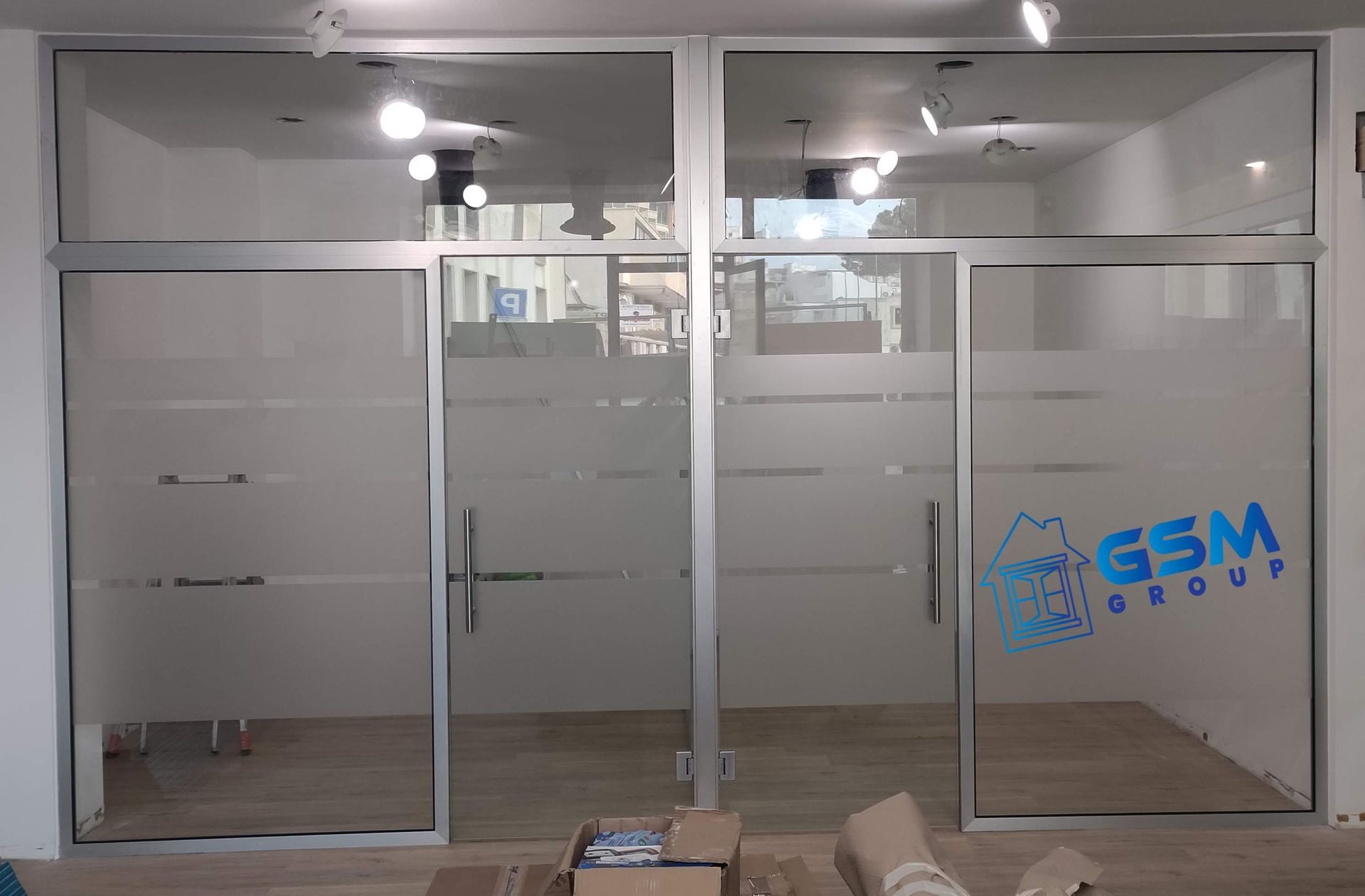 Un moderno ingresso per uffici con porte scorrevoli in vetro satinato e il logo blu 