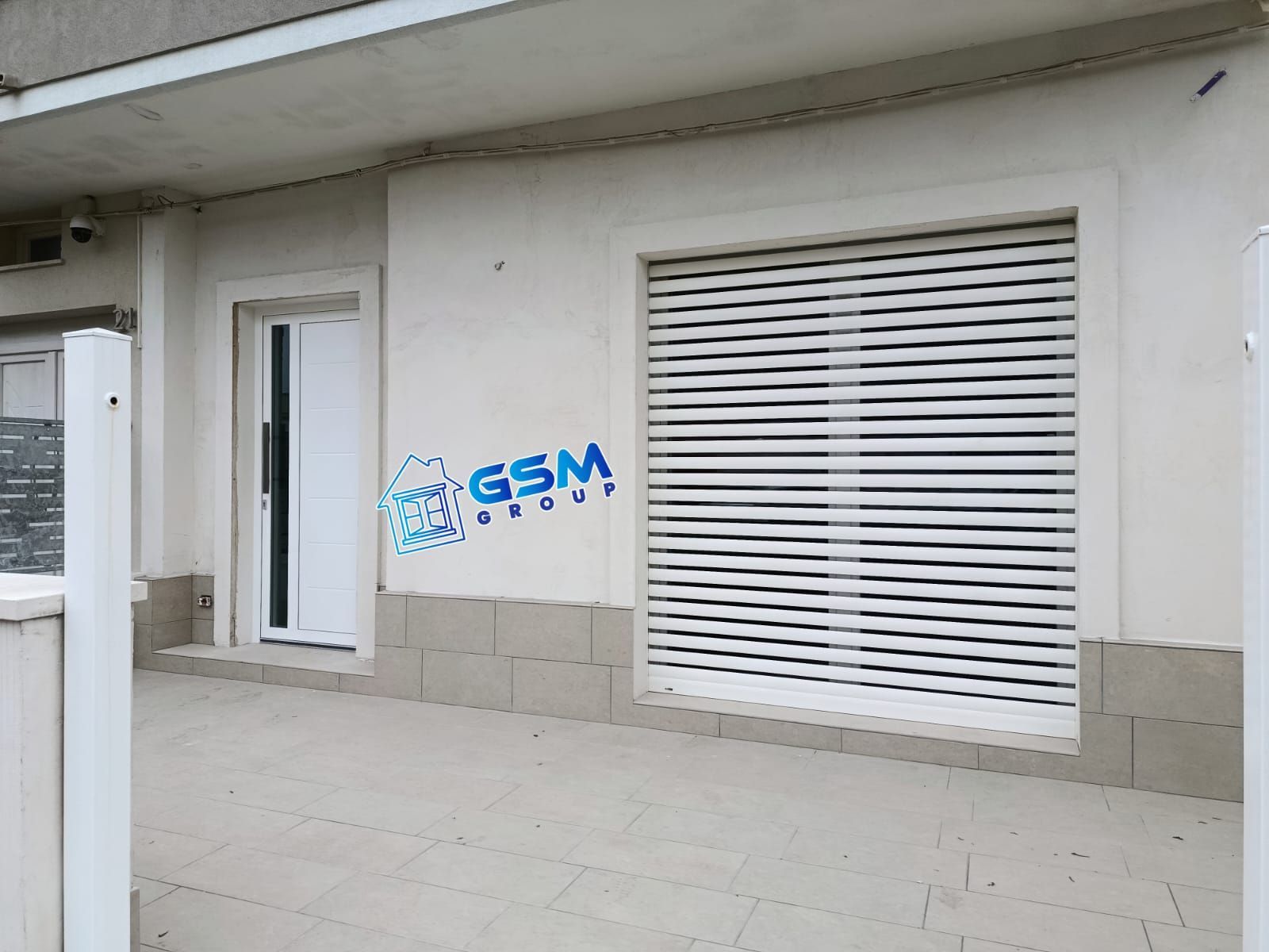 Primo piano di una zanzariera con vista sfocata degli edifici e del fogliame all'esterno.