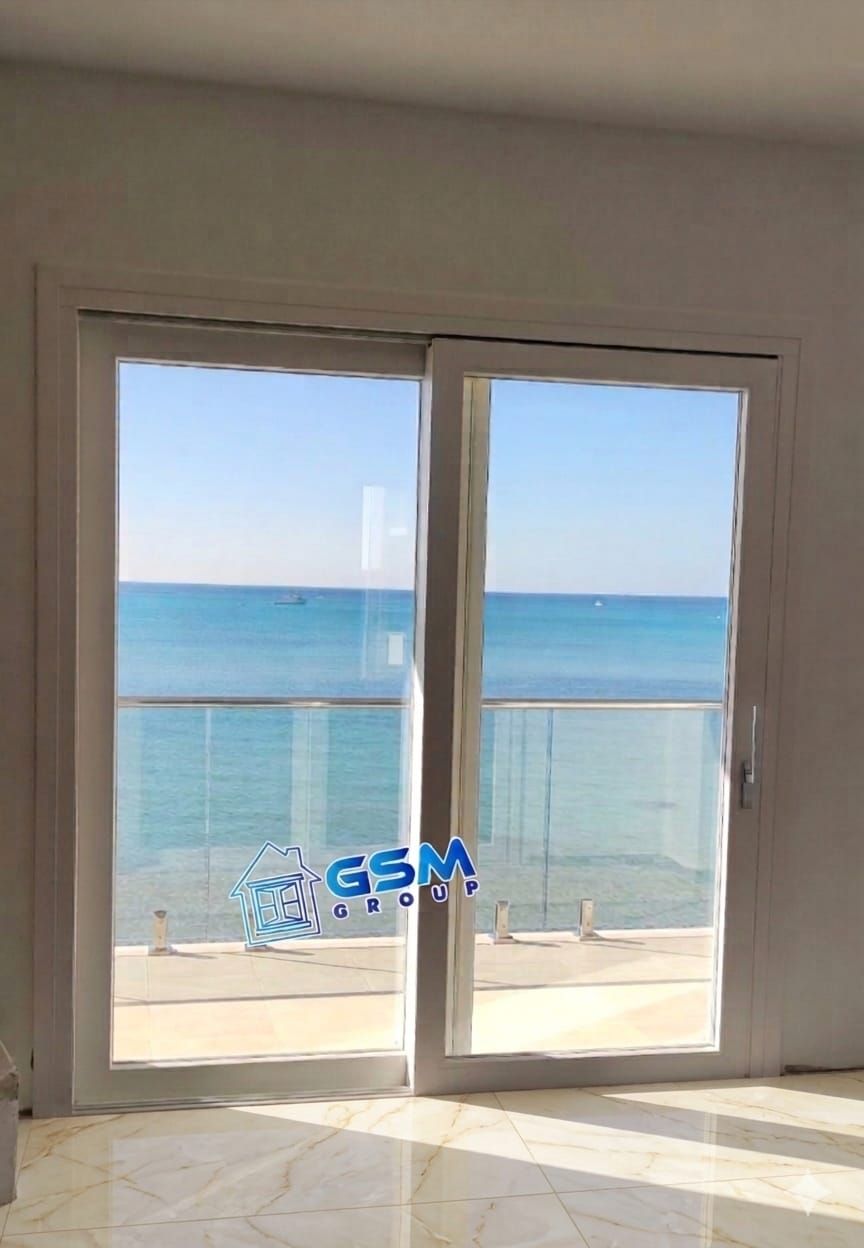 Una coppia di persiane di legno bianco aperte che si affacciano su un giardino.