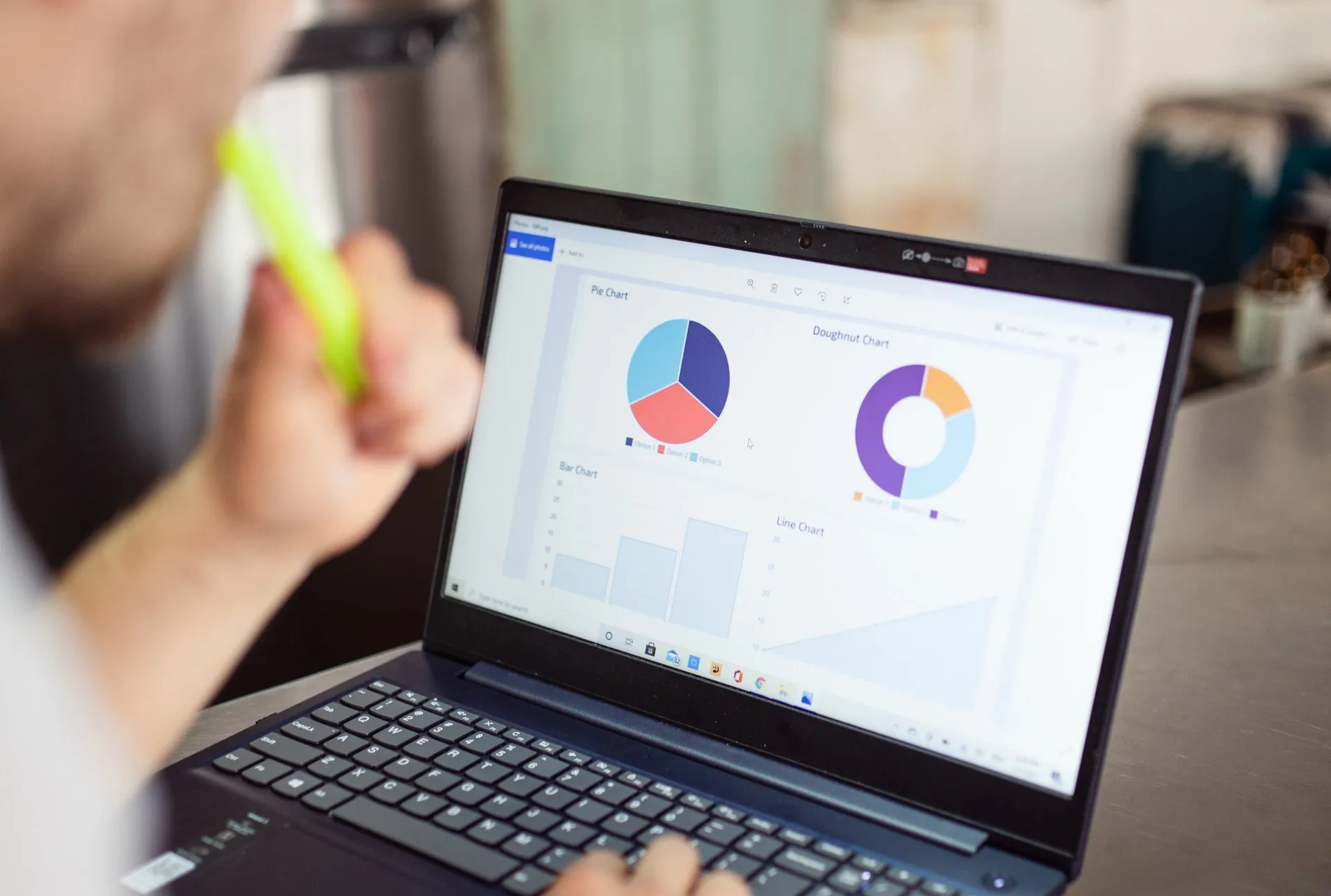 A person with a highlighter in their mouth reviews data charts on a laptop screen.