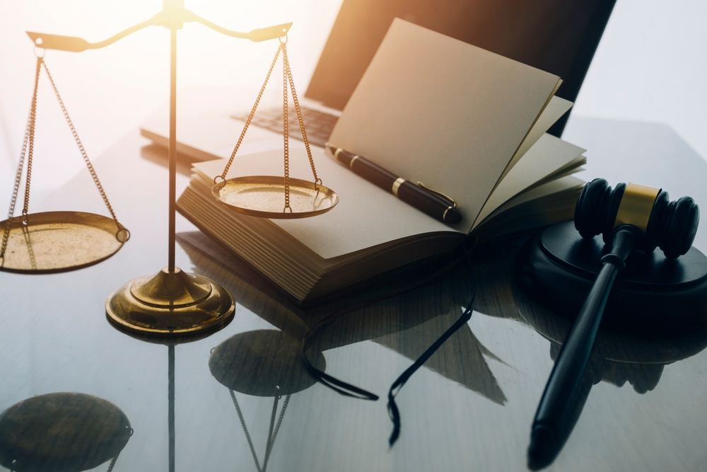 A scale of justice , a book , a pen , and a gavel on a table.