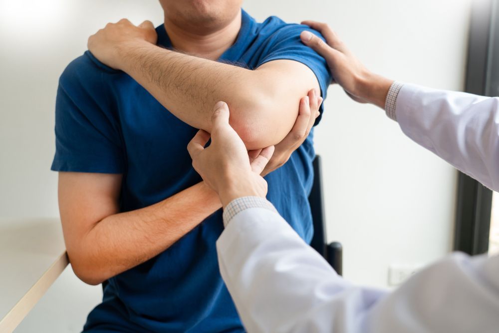 A man is getting his elbow examined by a doctor.