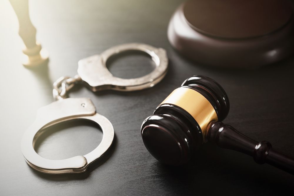 A pair of handcuffs and a judge 's gavel on a table.