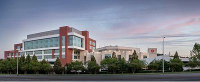 Modern building with red brick and glass facade, under a dusky sky.