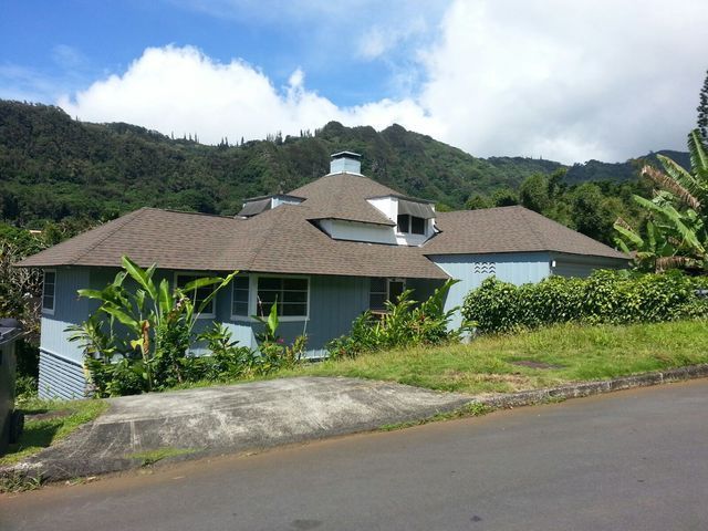 A house with a brown roof is surrounded by mountains