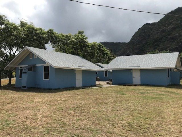 Two blue houses with white roofs in a grassy field